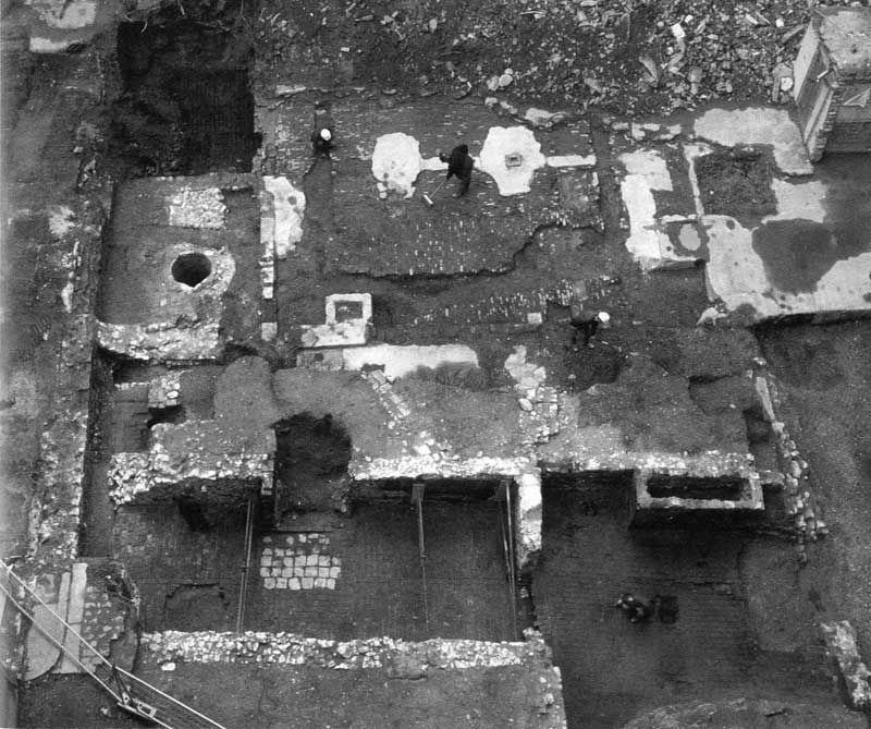 Aerial view looking west across Monument House (BPL95), with Building 7 rooms A and B (foreground), Building 6 and well (S7) (upper left) and courtyard (OA7) (upper centre) at. The Roman culvert and its access drop shaft have yet to be discovered